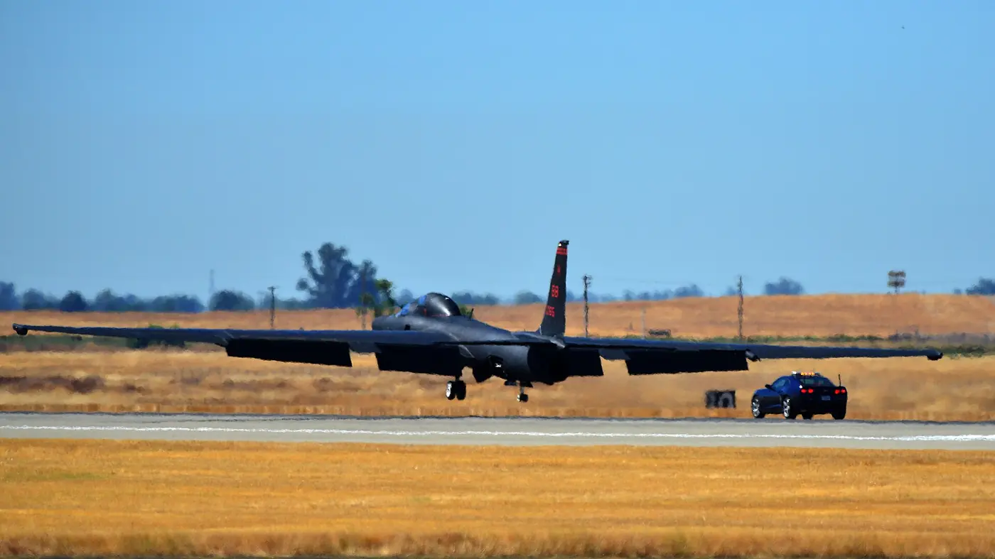 A U-2 a few feet above the runway with a black chase car close behind
